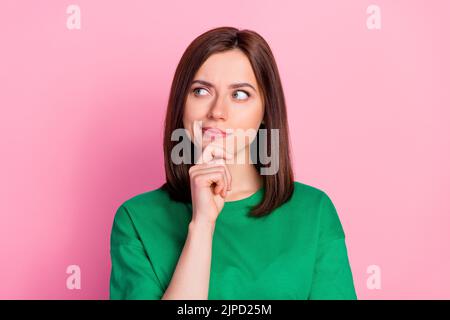 Ritratto fotografico di bella giovane signora sguardo scettico spazio vuoto non credo dubbio vestito alla moda verde look isolato su sfondo di colore rosa Foto Stock