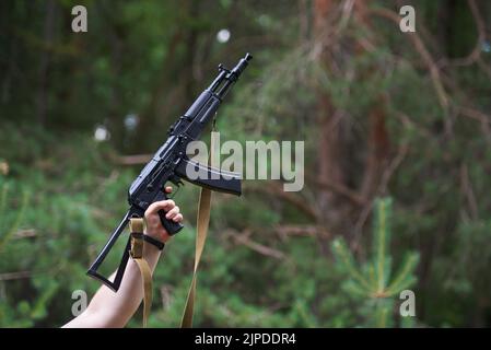 STARIY OSKOL, RUSSIA - 3 LUGLIO 2022: Fucile d'assalto russo Kalashnikov di AK-74 in mani maschili sullo sfondo della foresta Foto Stock