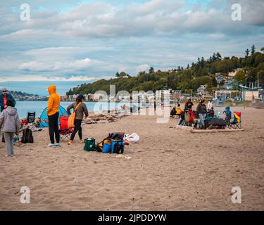 Un gruppo di persone che riposano sulla bellissima spiaggia sabbiosa di Alki a Seattle Foto Stock