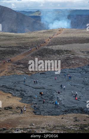 Escursionisti che passano il vecchio campo di lava sulla strada per l'eruzione del vulcano Meradalir, penisola di Reykjanes, Islanda, agosto 2022. Foto Stock