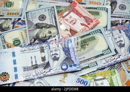 Pile di 100 $ cento dollari banconote in denaro americano con Arabia Saudita riyals banconote in denaro di 500 riyals, 100 e 50 riyal, America Foto Stock