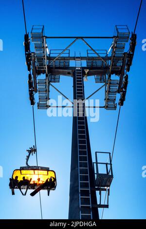 Sciatori seduti alla sedia di skilift e all'albero della funivia Foto Stock