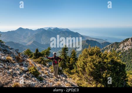 Un camminatore guarda giù sulla penisola di mani dalla collina di Mavrovouna sopra Milea nelle montagne di Taygetos, Peloponneso meridionale, Grecia. Foto Stock