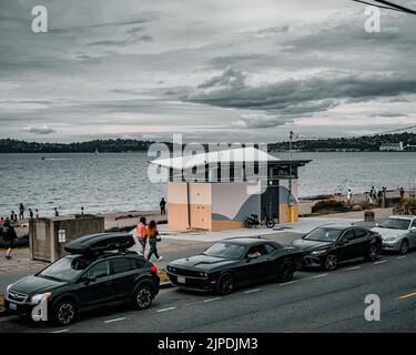 Una splendida vista delle auto parcheggiate accanto ad Alki Beach in una giornata buia a Seattle Foto Stock