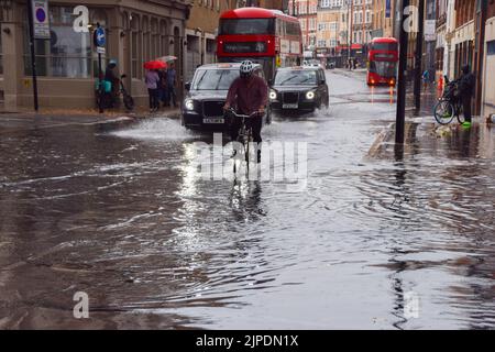 Londra, Regno Unito. 17th agosto 2022. Un ciclista attraversa una King's Cross Road allagata mentre piogge torrenziali e inondazioni improvvise colpiscono la capitale dopo mesi di siccità. Credit: Vuk Valcic/Alamy Live News Foto Stock