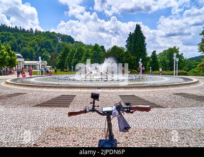 Marienbad, Repubblica Ceca, 30 giugno 2022: Fontana nel centro di Marienbad con un manubrio di bicicletta in primo piano come simbolo di gola ciclabile Foto Stock