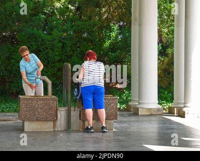 Marienbad, Repubblica Ceca, 30 giugno 2022: Le donne anziane attingono acqua curativa da una sorgente sotto i colonnati Foto Stock