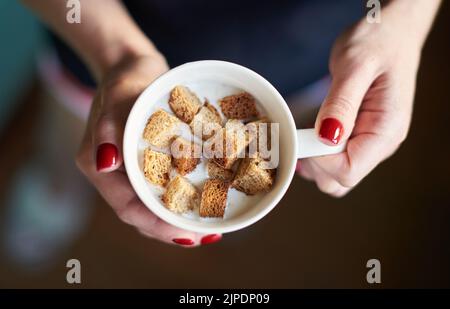Le mani femminili tengono yogurt al latte con cracker in una tazza. Delizioso dessert fatto in casa Foto Stock