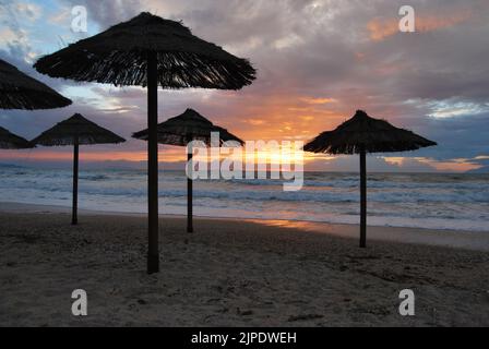 Tramonto con ombrelloni sulla spiaggia di Corfù in Grecia Foto Stock