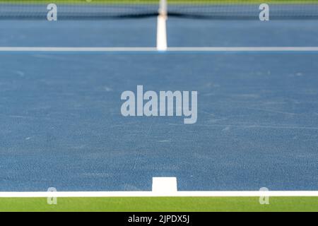 Foto ravvicinata del segno centrale alla base di un nuovo campo da tennis blu all'aperto con linee bianche. Foto Stock