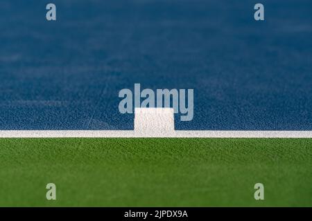 Foto ravvicinata del segno centrale alla base di un nuovo campo da tennis blu all'aperto con linee bianche. Foto Stock