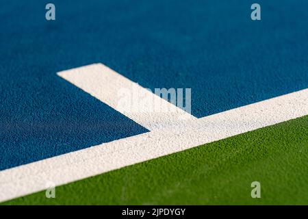 Foto ravvicinata del segno centrale alla base di un nuovo campo da tennis blu all'aperto con linee bianche. Foto Stock