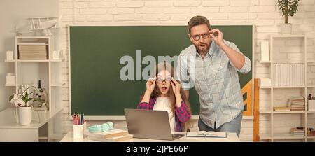 sorpresi papà e figlia vicino al clackboard. torna a scuola. educazione infantile. Foto Stock