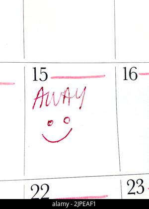 Immagine verticale di un testo rosso 'Away' e di un volto sorridente contrassegnato su un calendario Foto Stock