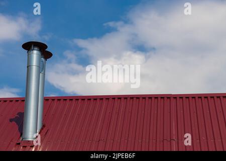 un camino che sporge da un tetto rivestito di ferro. Foto di alta qualità Foto Stock