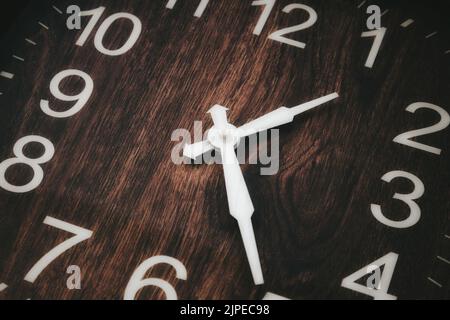 Primo piano di un orologio analogico in legno con numeri bianchi e lancetta dell'ora e dei minuti che mostra l'ora Foto Stock