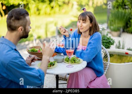 Giovane uomo e donna che mangiano cibo sano, trascorrendo l'estate insieme all'aperto Foto Stock