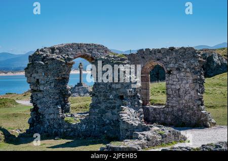 Le rovine della chiesa di San Dwynwens sull'isola di Anglesey. La croce celtica si vede attraverso la finestra della chiesa Foto Stock
