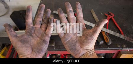 Immagine delle mani sporche di un fabbro che lavora nella sua officina con gli strumenti del background commerciale. Fai da te il lavoro. Foto Stock