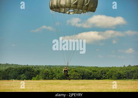 Un paracadutista tedesco atterra sulla Glen Rock Drop zone durante il Leapfest 2022 a Exeter, Rhode Island, 6 agosto 2022. Leapfest è il più grande evento e concorso internazionale per l'addestramento del paracadute statico di lunga data, organizzato dal comando della truppa del 56th, dalla Guardia nazionale dell'esercito del Rhode Island, per promuovere la formazione tecnica di alto livello e l'esprit de Corps all'interno della comunità internazionale di Airborne. (STATI UNITI Foto della Guardia Nazionale militare di SPC. Jonathan Santana) Foto Stock