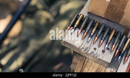 Primo piano di pallottole del fucile su nastro per machinegun immagazzinato su un tavolo di legno. Gamma di cottura. Messa a fuoco in primo piano. Scatto orizzontale. Foto di alta qualità Foto Stock
