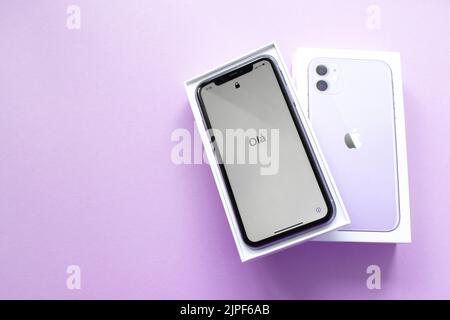 Mosca, Russia, Maggio 2021: Un nuovo modello di iPhone 12 di colore viola in una scatola aperta di marca su uno sfondo lilla. Sullo schermo dell'iPhone, un benvenuto in po Foto Stock