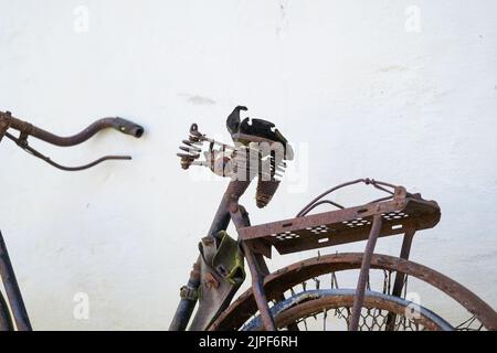 Vecchia bicicletta arrugginita appoggiata contro una parete bianca, primo piano Foto Stock