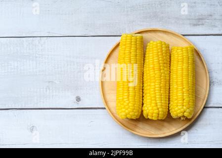 mais dolce cotto su sfondo piatto di legno, pannocchie di mais maturo al vapore o mais bollito per cibo vegan cena o snack Foto Stock