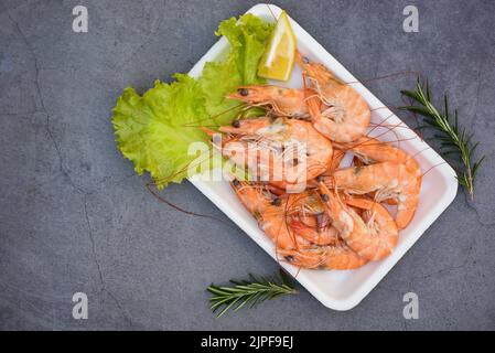 Gamberetti freschi su piatto vassoio di plastica con spezie al limone ed erbe, gamberetti bolliti che cucinano cibo nel ristorante di pesce - vista dall'alto Foto Stock