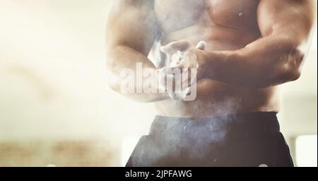 Avere una presa forte è la chiave: Un giovane uomo irriconoscibile che gli spolverò le mani durante un allenamento in palestra. Foto Stock