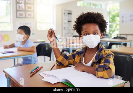 Bambino o studente in classe durante il periodo di covid, indossando una maschera per l'igiene e la protezione dall'influenza del coronavirus. Ritratto asilo nido, prescolare o elementare Foto Stock