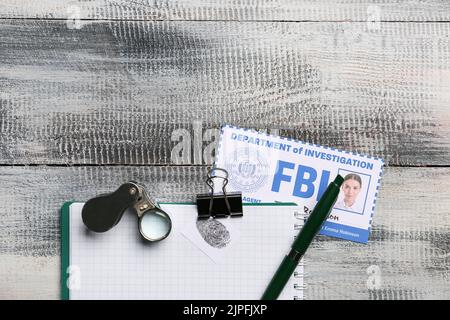 Notebook con lente di ingrandimento e documento dell'agente FBI su sfondo in legno Foto Stock