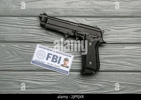 Pistola con documento di agente FBI su sfondo legno Foto Stock