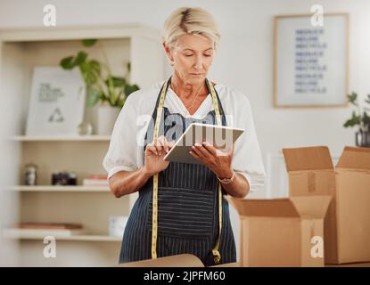 . Ordine online, imballaggio di pacchi o confezioni durante il controllo delle vendite di tablet in negozio, negozio di abbigliamento o officina. Confezioni mature su misura o da marinaio Foto Stock