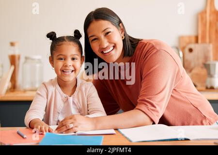 Madre che aiuta, insegna ed educa figlia con i compiti a casa. Ritratto di felice, amorevole e sorridente mamma e bambina impegnata con educativo Foto Stock