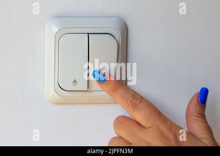 La mano della donna, spegnendo il quadro elettrico per l'economia energetica Foto Stock