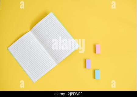 vista dall'alto del notebook aperto, su sfondo giallo brillante con gomma pastello Foto Stock
