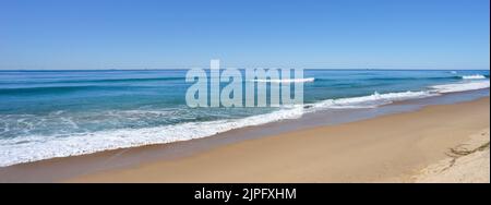 Una tranquilla scena di onde da surf che si snoda su una spiaggia sabbiosa lungo la riva di Kawana sulla Sunshine Coast Queensland Australia in una soleggiata giornata invernale. Foto Stock