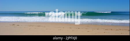 Panorama di onde da surf che si avvolgono sulla spiaggia in una tranquilla, soleggiata, giornata invernale. Foto Stock