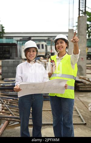 Donna asiatica architetto e supervisore discutere sul piano durante la visita di un nuovo edificio Foto Stock