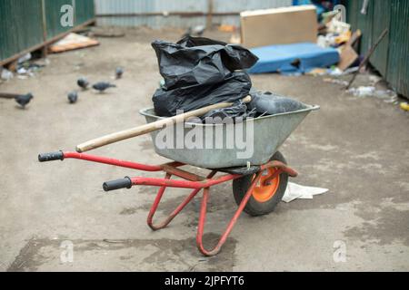 Carrello da giardino con bustine nere all'interno. Pulizia del territorio. Trasporto di rifiuti. Dettagli spazzatura. Foto Stock