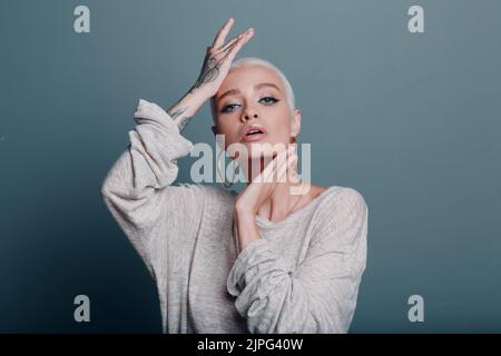 Giovane donna milleniale con ritratto dei capelli biondi corti che fa il massaggio autofacciale dello yoga del viso per la pelle Foto Stock