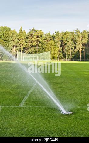 impianto sprinkler a terra che innaffia il campo sportivo Foto Stock