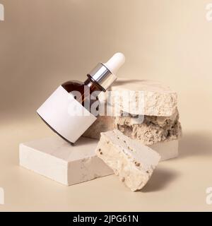 Flacone contagocce cosmetico marrone con etichetta vuota su pietre in travertino beige su giallo chiaro, primo piano, prodotto di bellezza Skincare Mockup. Naturale eco frien Foto Stock