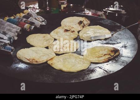 India pancake Roti cucina. Torte fritte su un grande foglio di cottura. Paratha Foto Stock