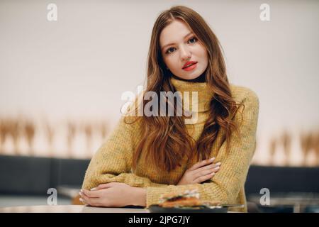 Giovane donna che mangia sandwich al bar interno. Foto Stock