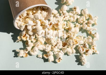 Popcorn sparso dalla tazza di carta di mestiere. Concetto di cinema o visione della TV. Foto Stock