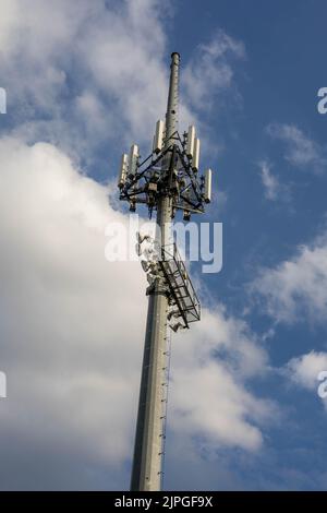 torre del telefono cellulare e torre faro accanto a un campo sportivo Foto Stock