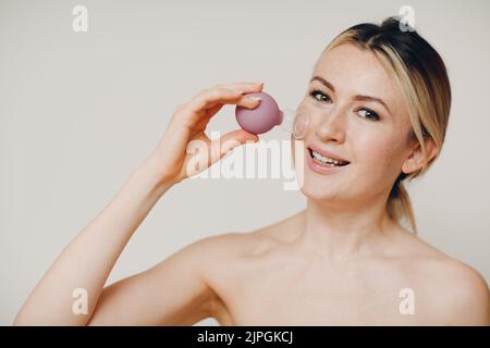 Procedura di terapia di imbutitura, donna con piccola tazza medica per il viso Foto Stock