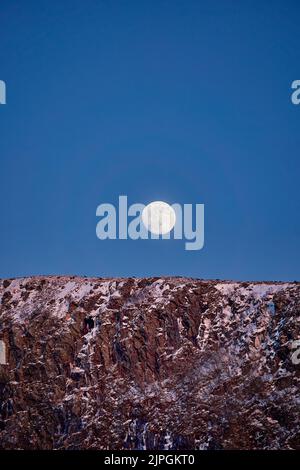 La luna che si innesca sopra la montagna di Flø, Ulsteinvik, Norvegia. Foto Stock